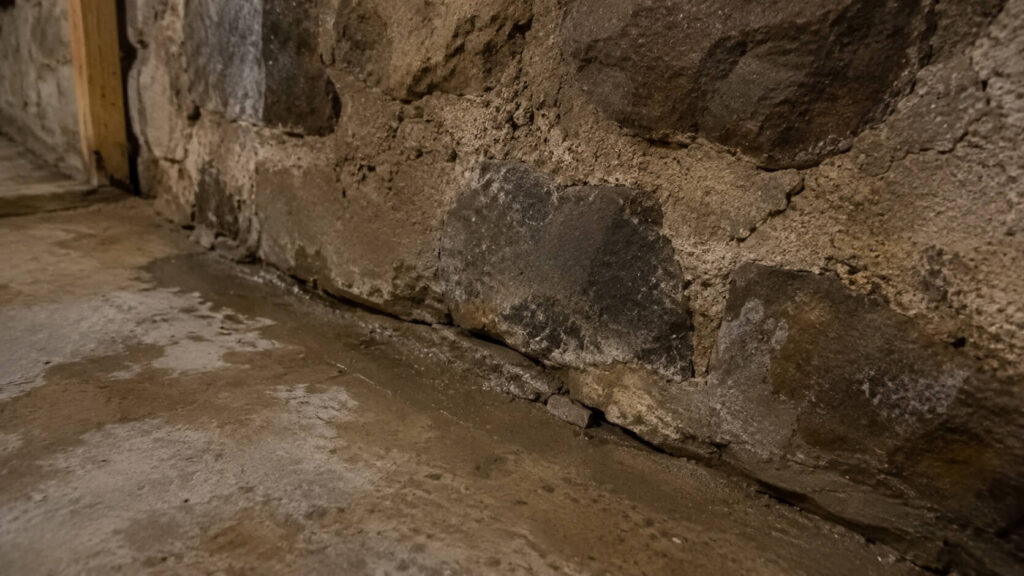 Fissure visible dans le mur et le sol d’une cave, illustrant un risque potentiel de radon